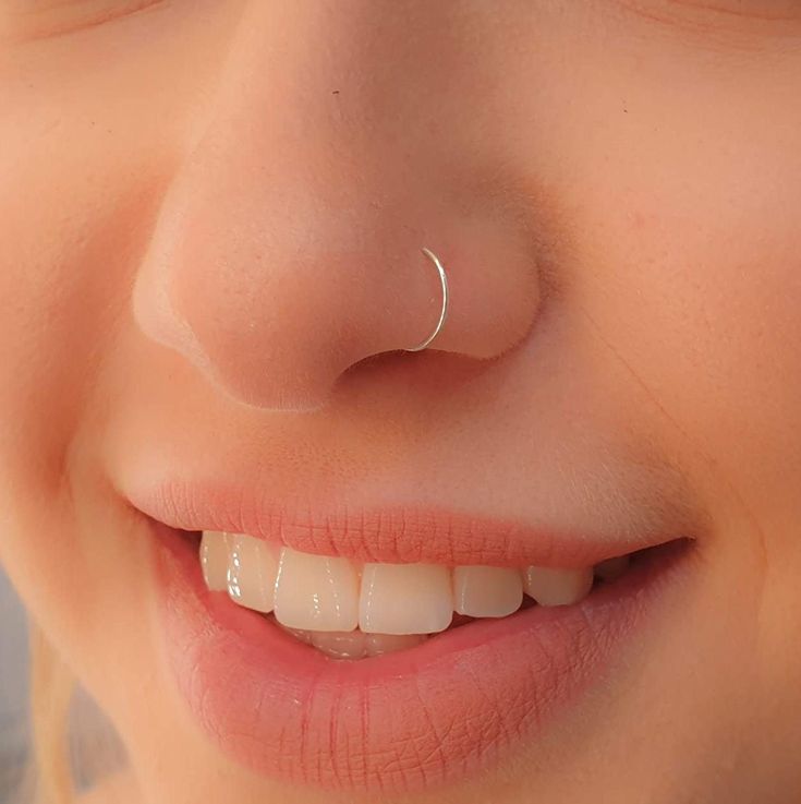 a close up of a person's smile with a nose ring on their nose