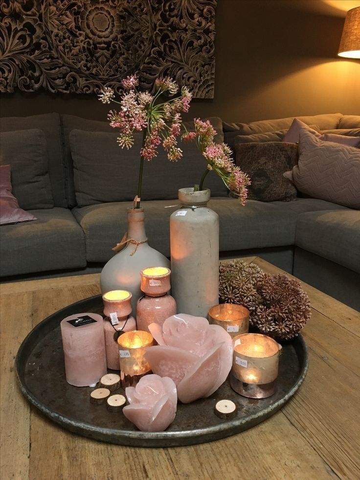 candles and vases on a tray in front of a couch