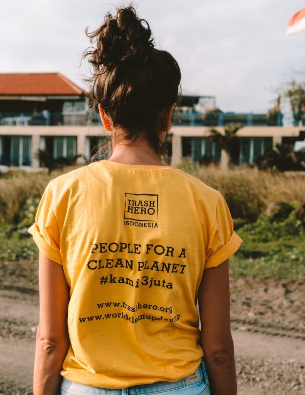 a woman wearing a yellow t - shirt with people for a clean planet written on it