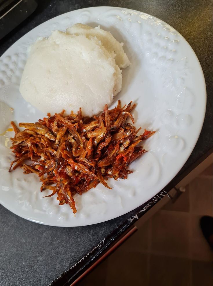 a white plate topped with rice and fried food on top of a kitchen counter next to a stove