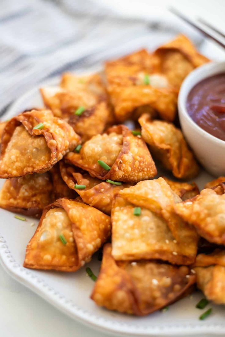 a white plate topped with fried food next to a bowl of dipping sauce