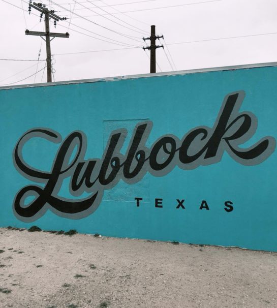 a blue sign that reads lubbock texas on it's side in front of some power lines