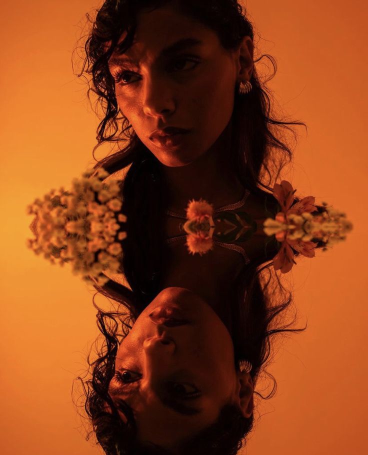 a woman holding flowers in her hands with an orange light behind her and she is looking at the camera