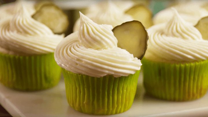 several cupcakes with white frosting and cucumber slices on the top