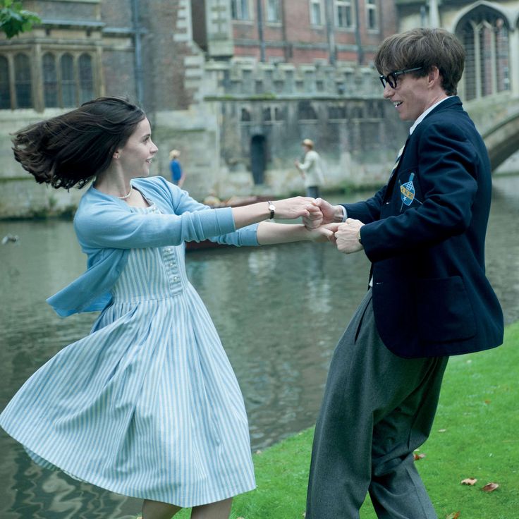 a man and woman dancing in front of a river