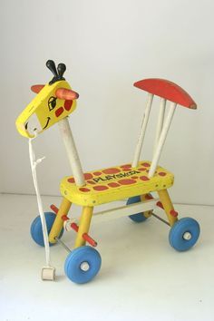 a toy giraffe sitting on top of a blue and yellow tricycle with wheels