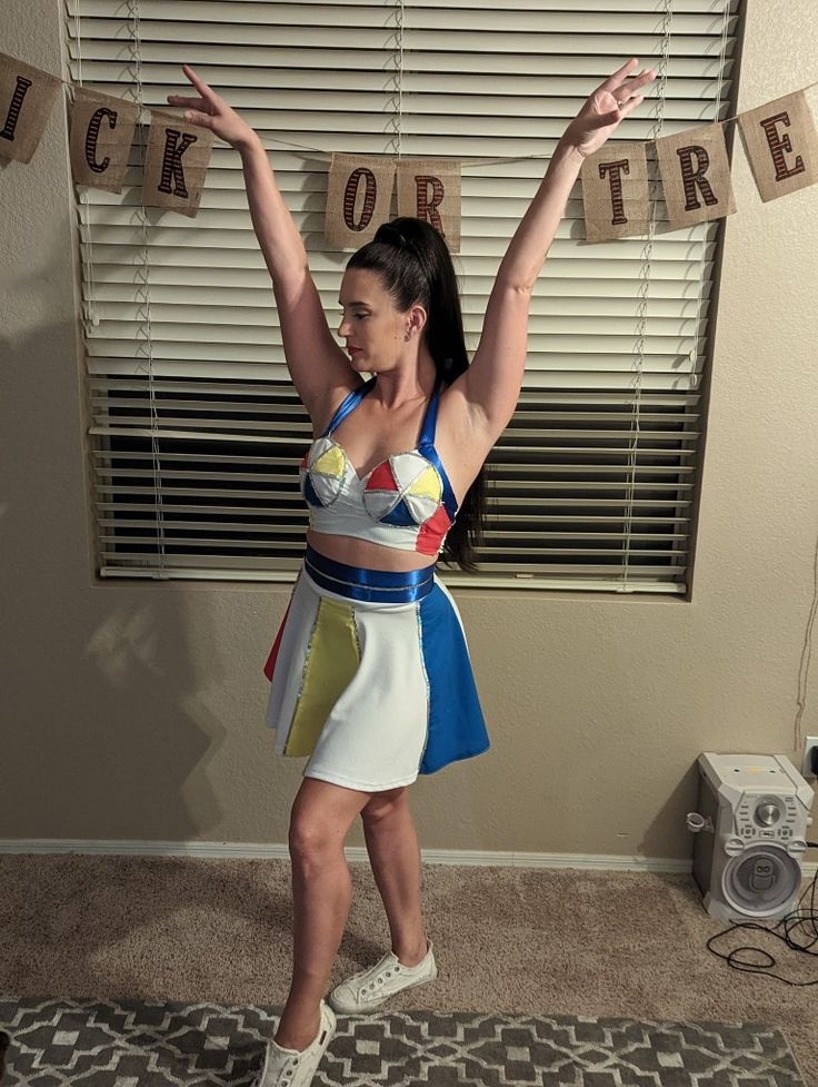 a woman standing in front of a window with her arms up and two letters hanging on the wall