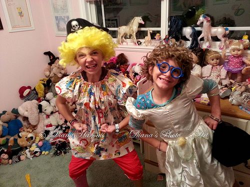 two children dressed up in costumes and wigs posing for the camera with stuffed animals all around them