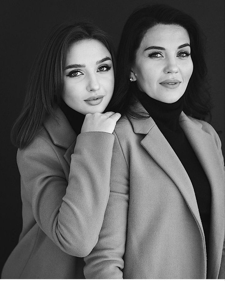 two beautiful women standing next to each other in black and white photo posing for the camera