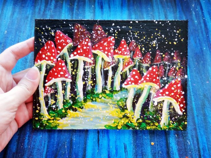 a person holding up a small painting of mushrooms