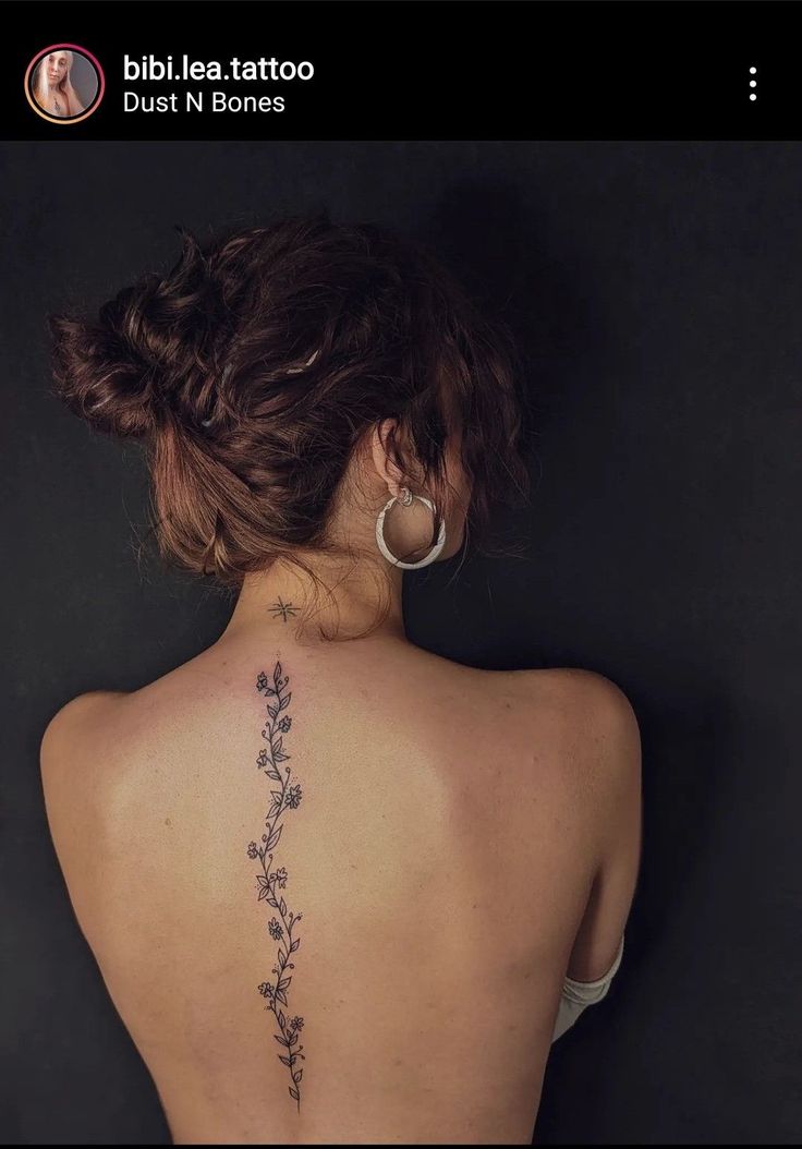 the back of a woman's neck with small flowers on her left side tattoo