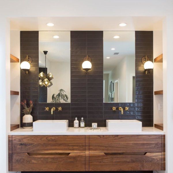 a bathroom with two sinks, mirrors and lights on the wall in front of it