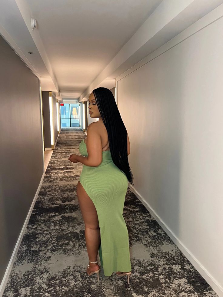 a woman in a green dress is walking down an empty hallway with no shoes on