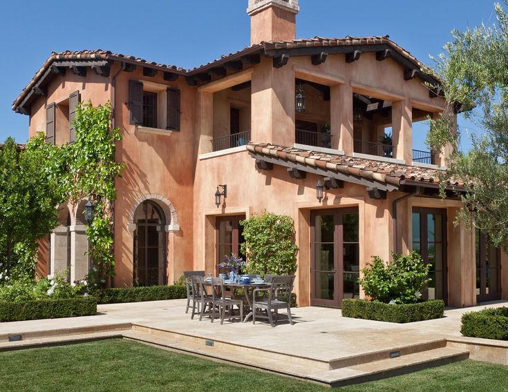 an outdoor dining area in front of a large house