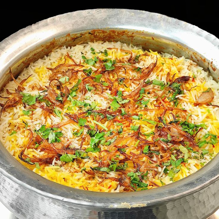 a large metal bowl filled with rice and vegetables