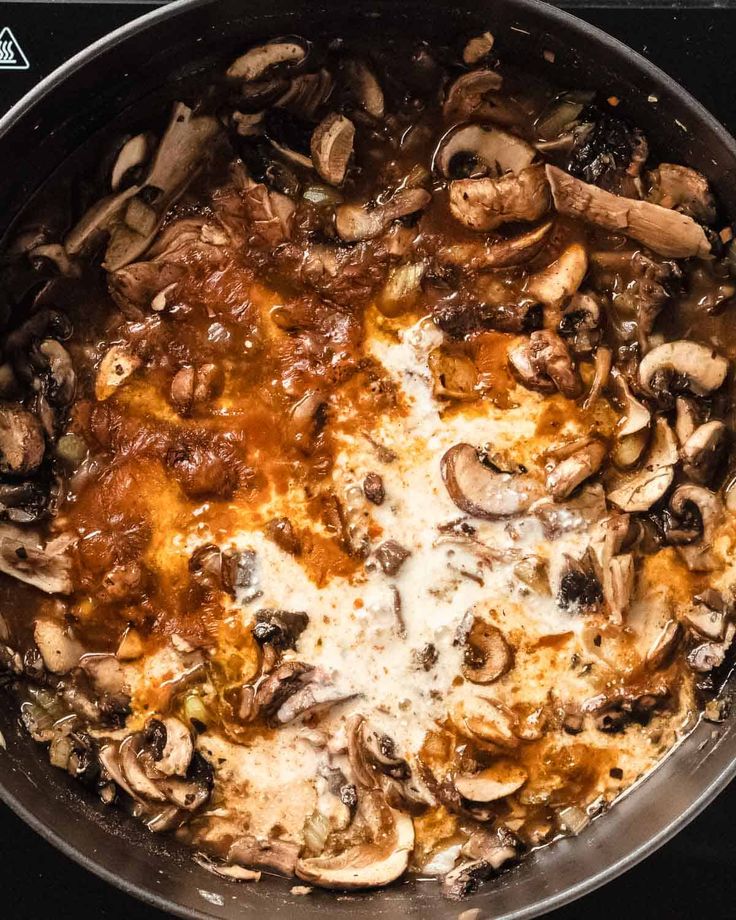 a pan filled with mushrooms and cheese on top of a stove