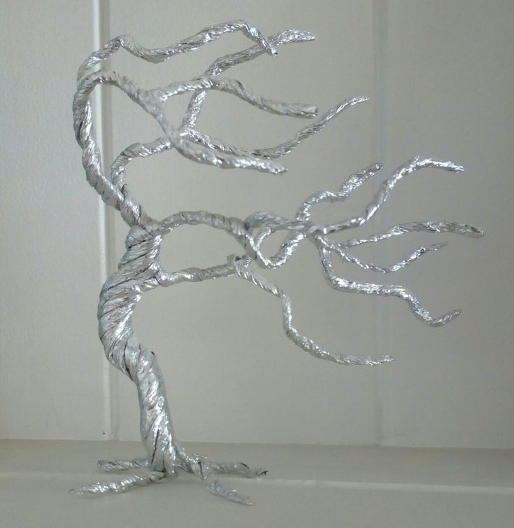 a metal tree sculpture sitting on top of a white shelf