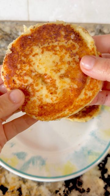 a person holding up a piece of food on a plate in front of a marble counter top