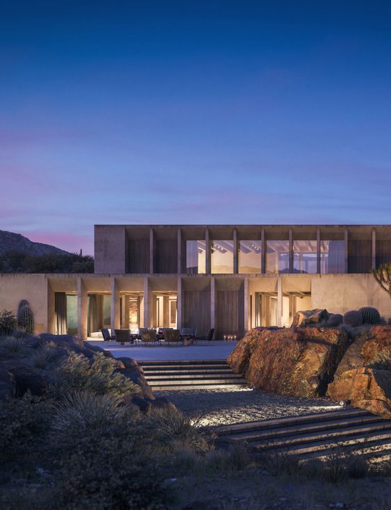 an exterior view of a modern house with stairs leading up to the front door at dusk