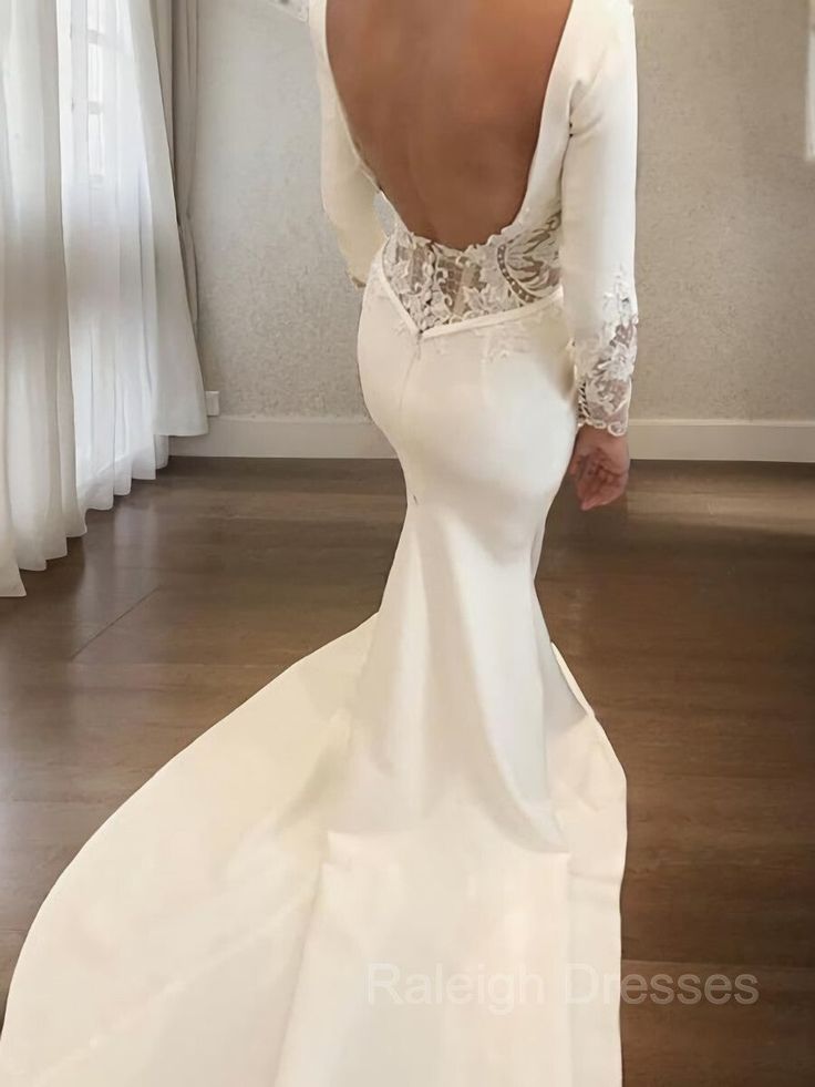 a woman in a white wedding dress is looking at her back while standing on the floor