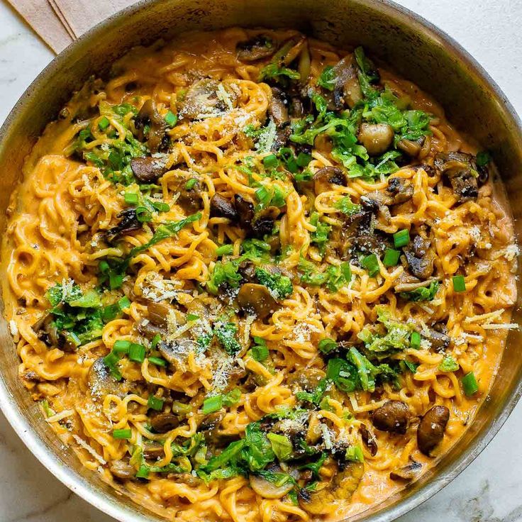 pasta with mushrooms and parsley in a skillet on a marble countertop, ready to be eaten