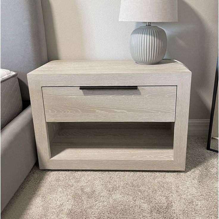 a white lamp sitting on top of a wooden table next to a gray couch in a living room