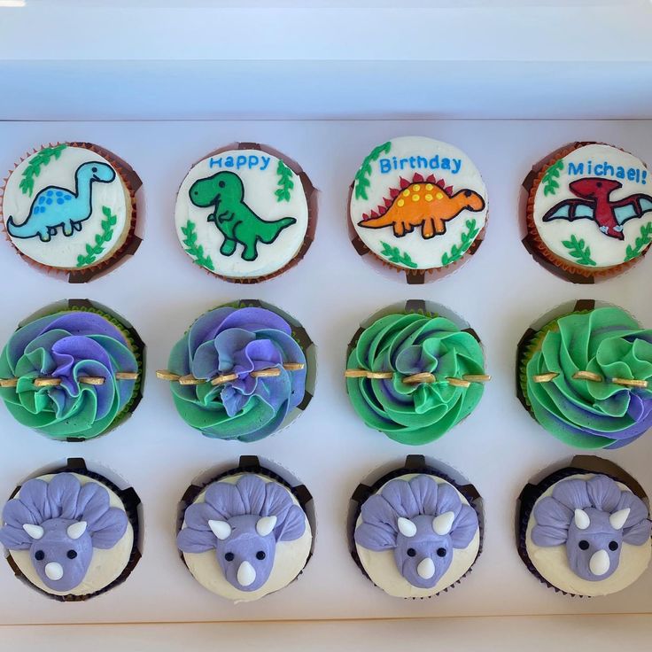 cupcakes decorated with dinosaur designs in a box