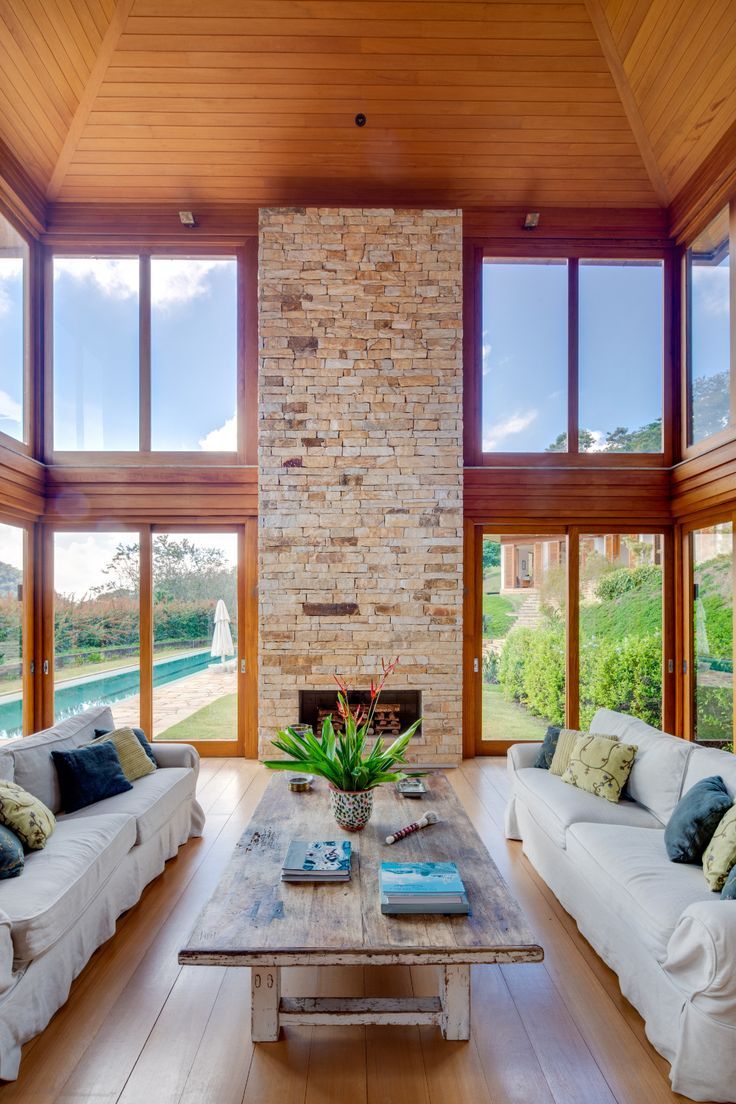 a living room filled with white couches next to a tall brick wall and windows