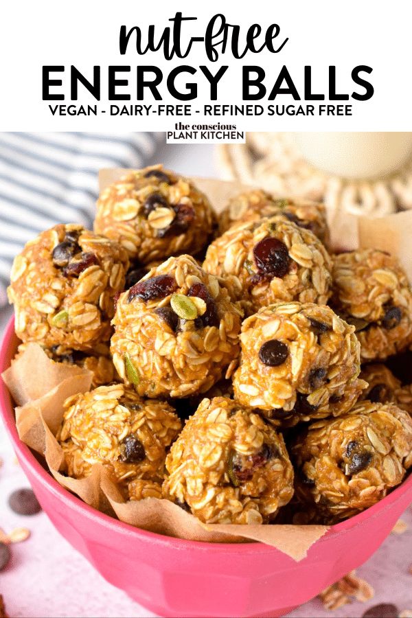 a pink bowl filled with granola energy balls on top of a table next to chocolate chips