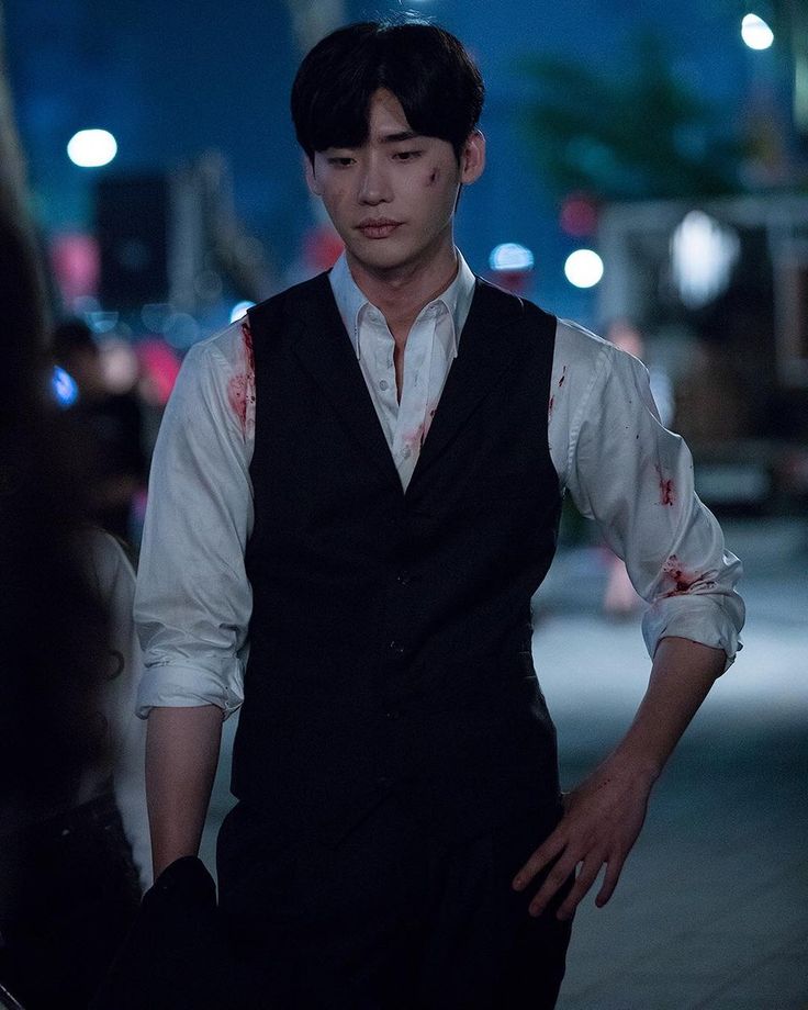 a man with blood all over his shirt and tie is standing in the street at night