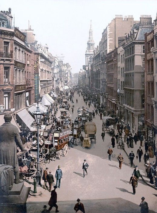 an old photo of a busy city street with people walking and sitting on the sidewalks