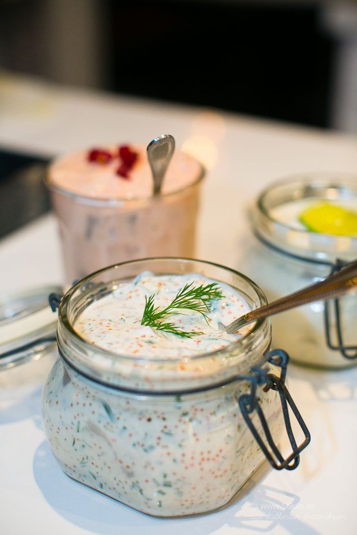 two jars filled with food sitting on top of a white table next to spoons