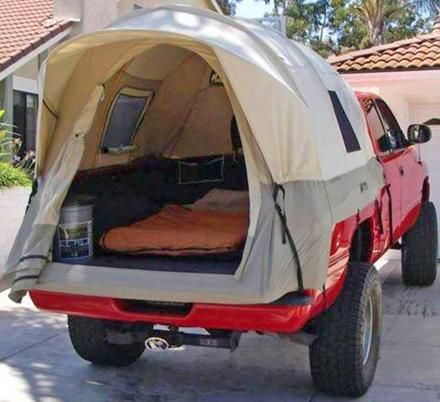 a truck with a tent attached to it's bed in front of a house