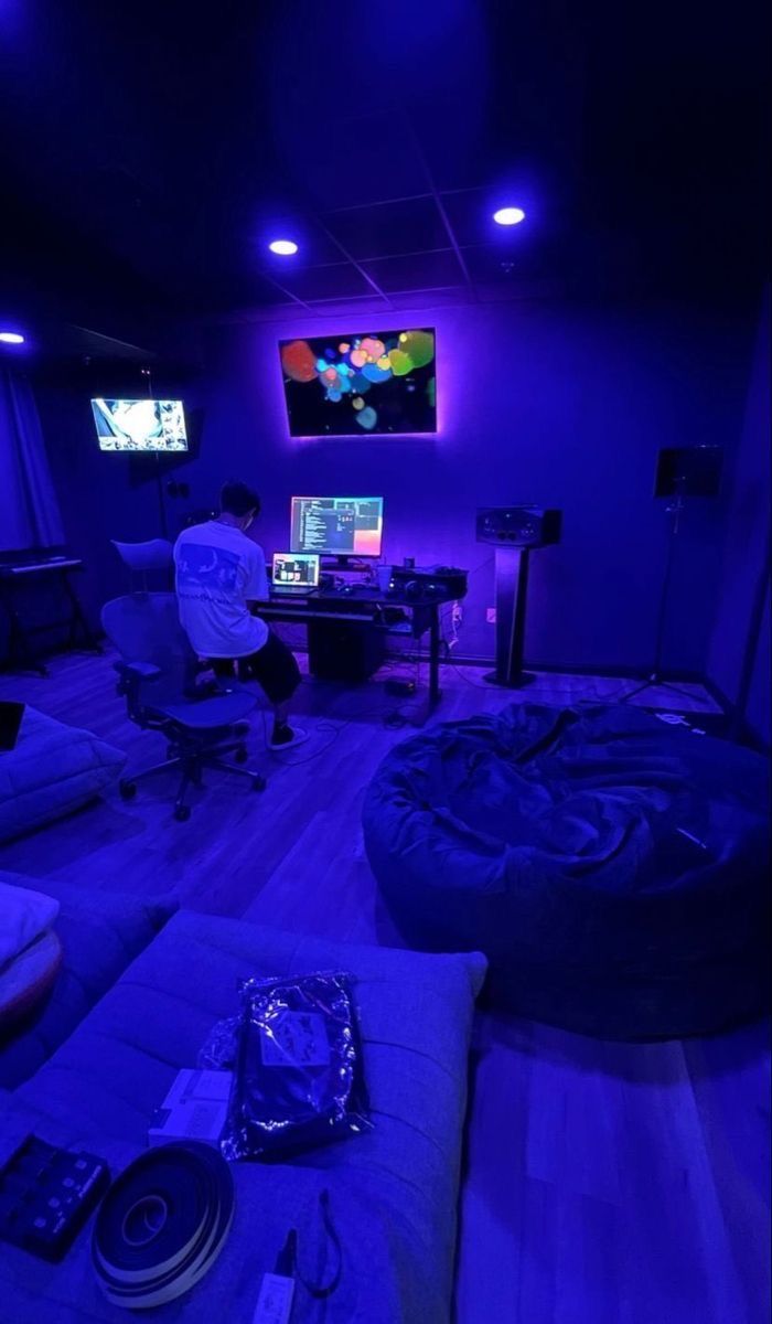 a man sitting in front of a tv on top of a wooden floor next to a couch