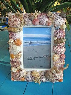 a photo frame with seashells around it on a table