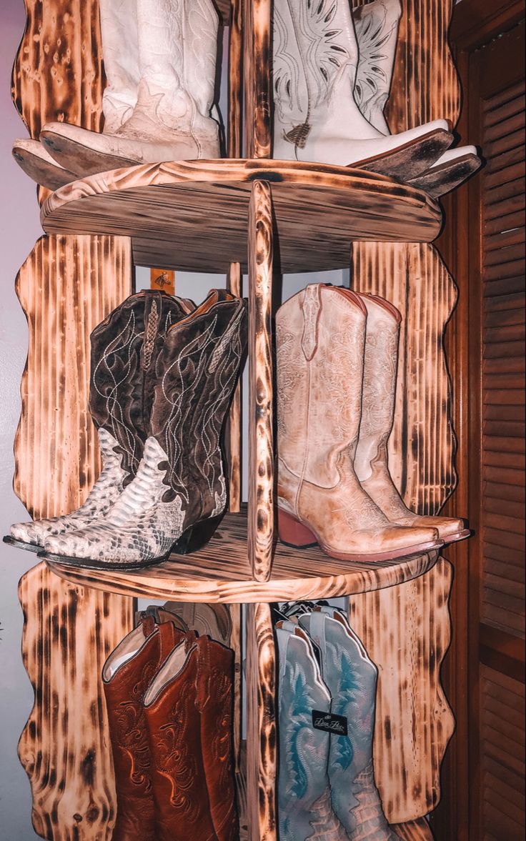 several pairs of cowboy boots sit on wooden shelves