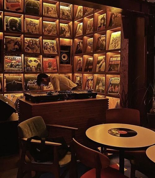 a room filled with tables and chairs next to a wall full of pictures on the walls