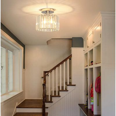 a hallway with white walls and wooden floors, a chandelier hanging from the ceiling