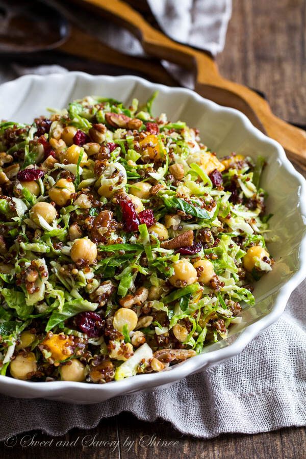 a white bowl filled with lettuce, nuts and cranberry salad on top of a wooden table