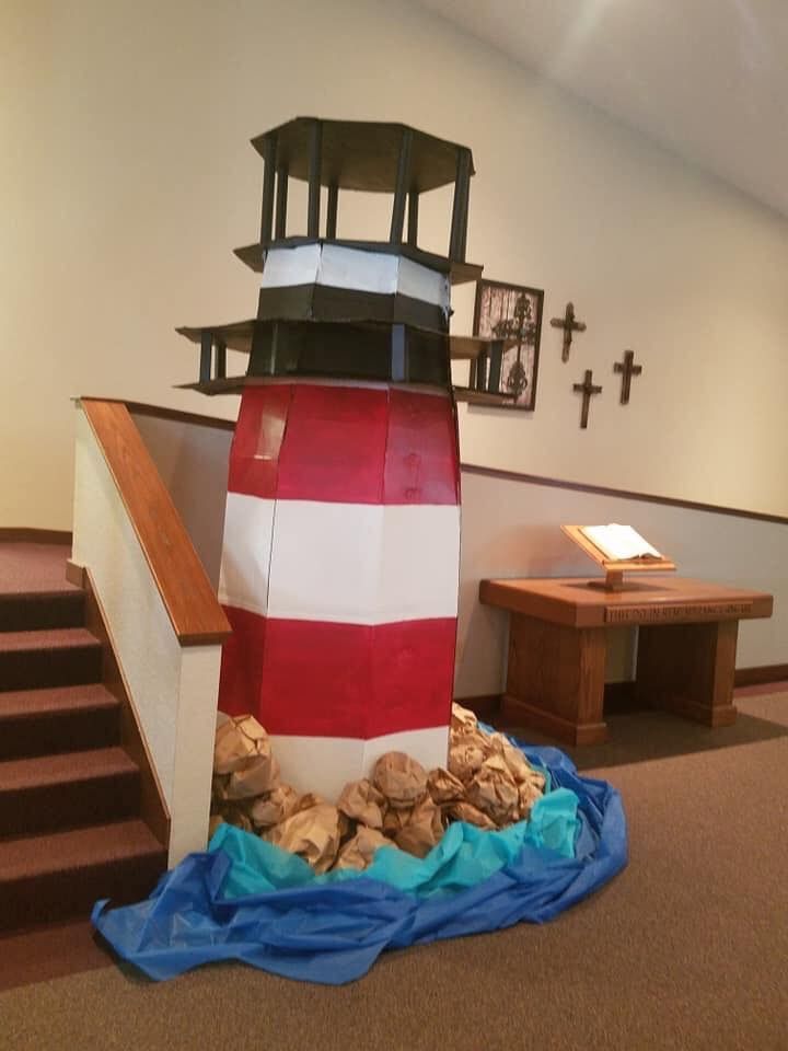 a red and white lighthouse made out of rocks on the ground next to some stairs