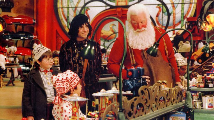 two children and an older man in costume standing next to a table full of toys