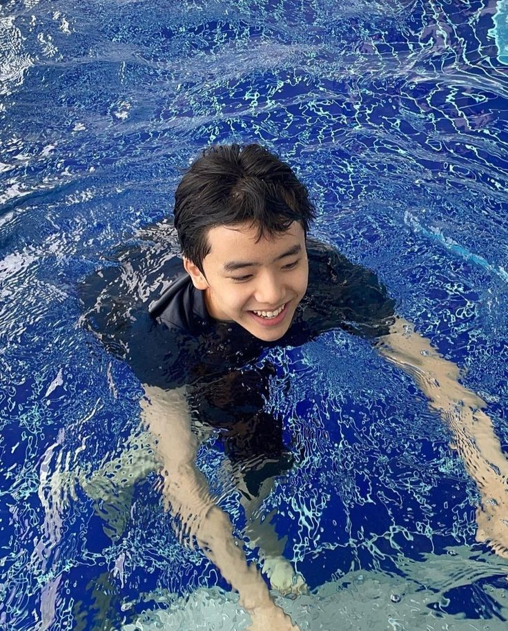 a young man swimming in a pool with his hands on the water's surface