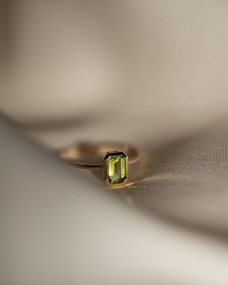 The octagon-shaped peridot on this ring is both eye-catching and elegantly simplistic. It is the perfect way to celebrate a special August birthday or simply adorn oneself with its stunning light green hue. Metrical : 14-karat Yellow Size: Band measures 1mm, Peridot measures 6x4mm Green Emerald Cut Stackable Rings For May Birthstone, Dainty Emerald Cut Solitaire Birthstone Ring, 14k Gold Emerald Cut Birthstone Ring, Dainty 14k Gold Birthstone Ring With Emerald Cut, Dainty 14k Gold Emerald Cut Birthstone Ring, Minimalist Emerald Cut Birthstone Ring With Bezel Setting, Minimalist May Birthstone Ring With Emerald Cut, Minimalist 14k Gold Emerald-cut Birthstone Ring, Minimalist 14k Gold Emerald Cut Birthstone Ring