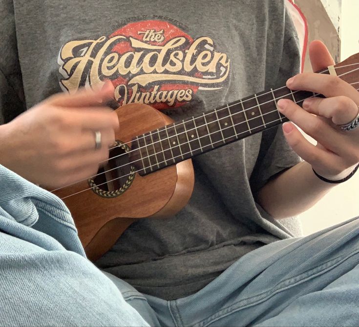 a person is playing an ukulele with their fingers and holding the fret