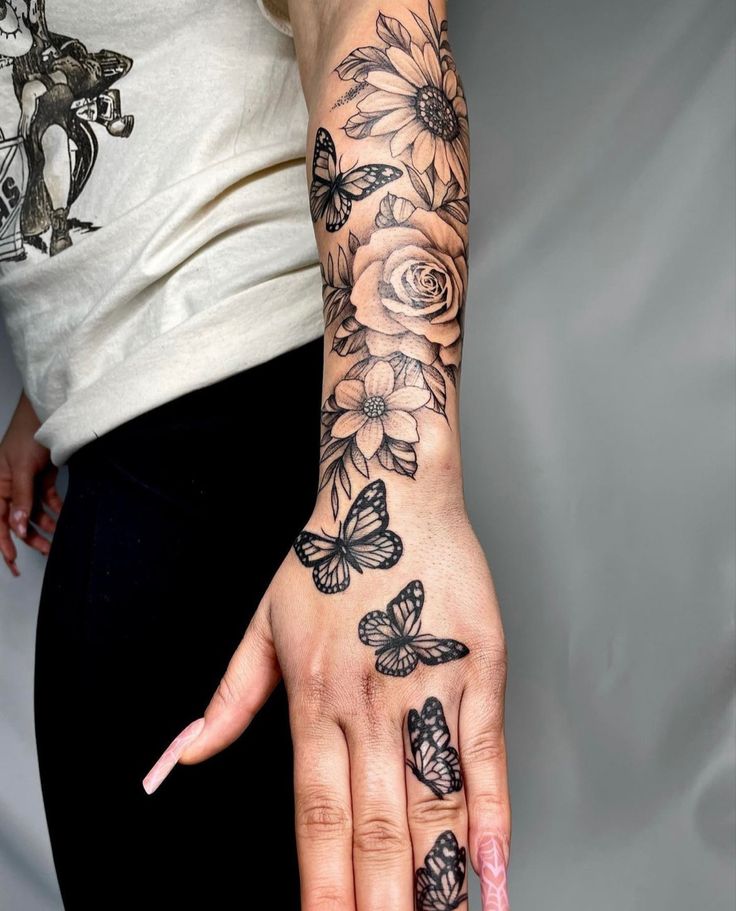 a woman's hand with flowers and butterflies on it, next to her right hand