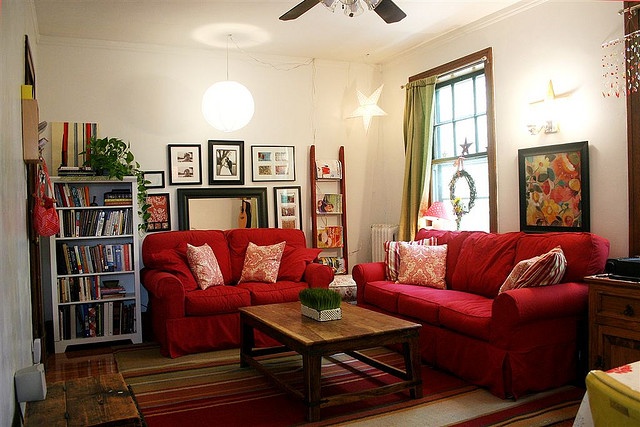 a living room with red couches and pictures on the wall above them in front of a window