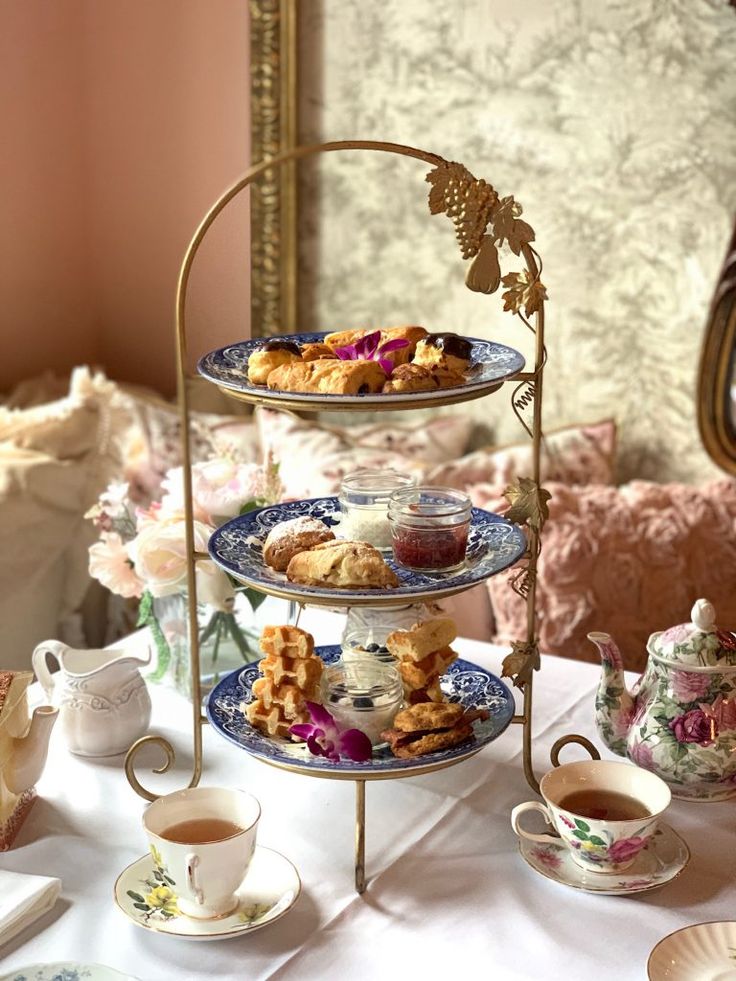 three tiered trays filled with pastries and tea cups on a table in front of a mirror