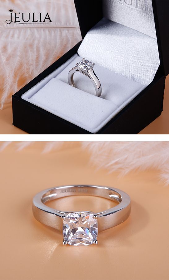 an engagement ring with a princess cut diamond sits in a box on top of a furnishing