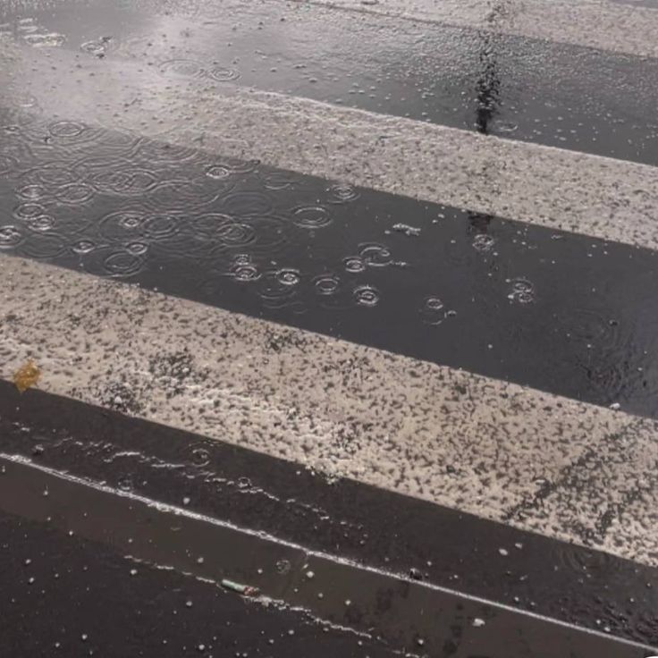 an umbrella sitting on top of a wet crosswalk next to a traffic light in the rain