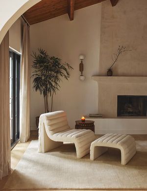 a living room with a fireplace and two white lounge chairs in front of the fire place